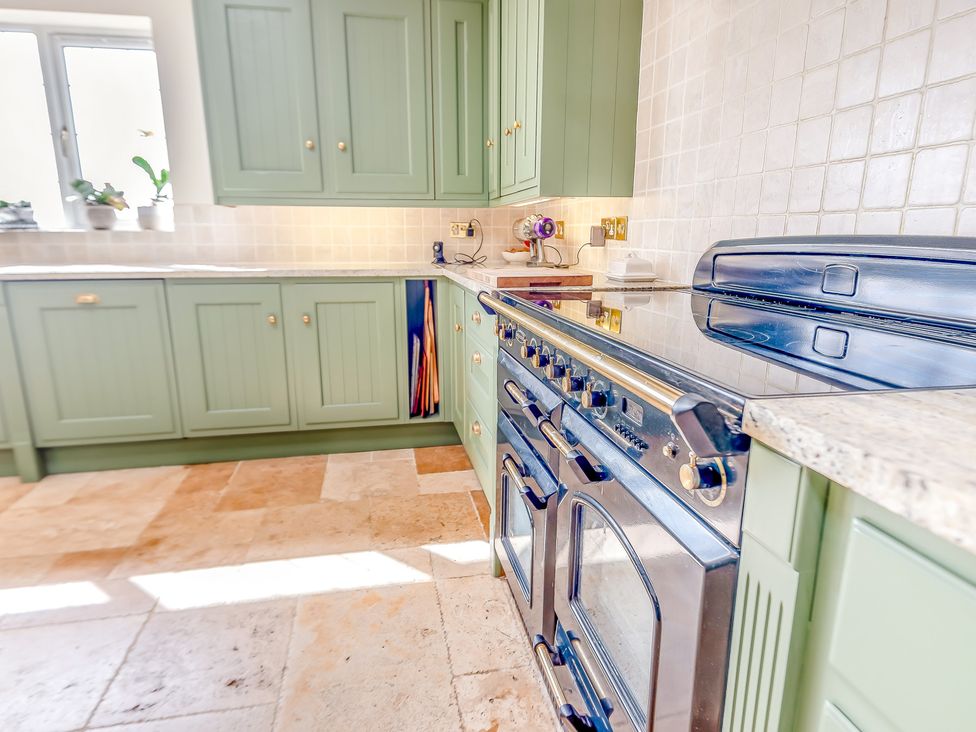A kitchen with green cabinets and a black oven at Underhill House