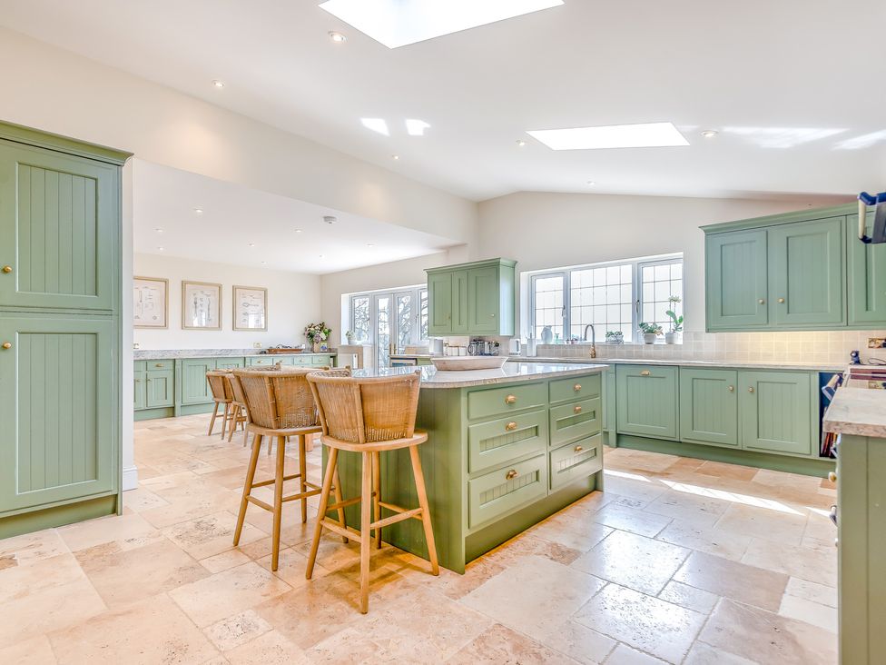 A kitchen with cabinets and bar stools at Underhill House
