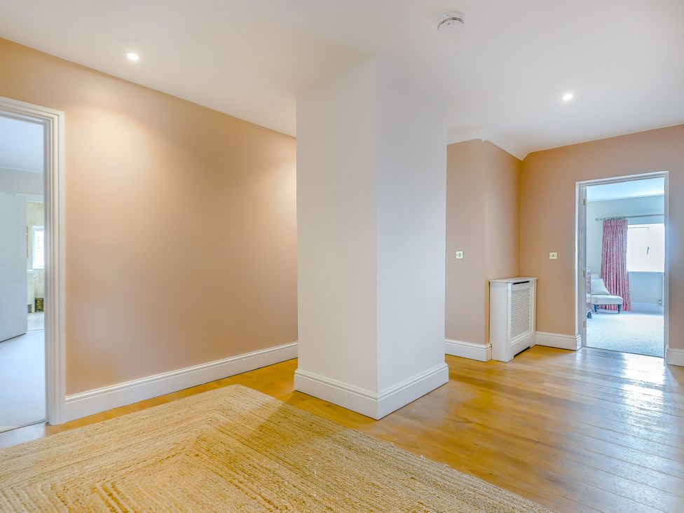 A hallway with a rug and doors leading to other rooms at Underhill House