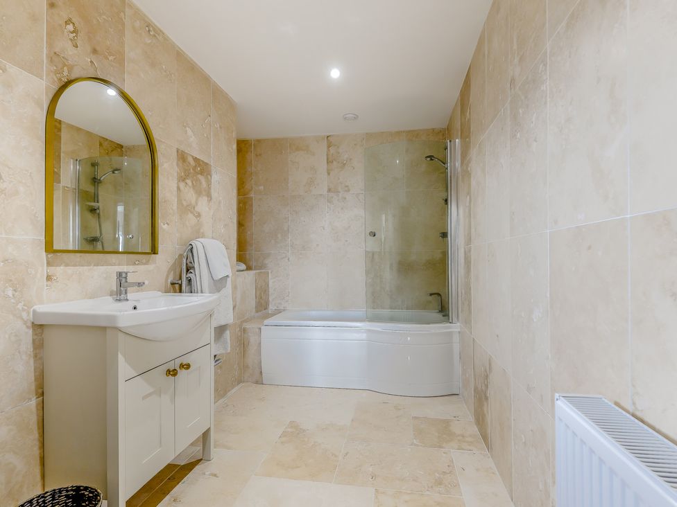 A bathroom with a bathtub, sink, and mirror at Underhill House
