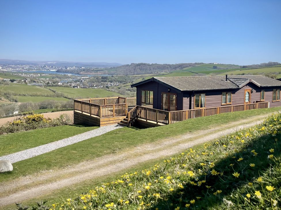 A lodge with a deck and a grassy area at Lowena Lodge Whitsand Bay Holiday Park near Millbrook