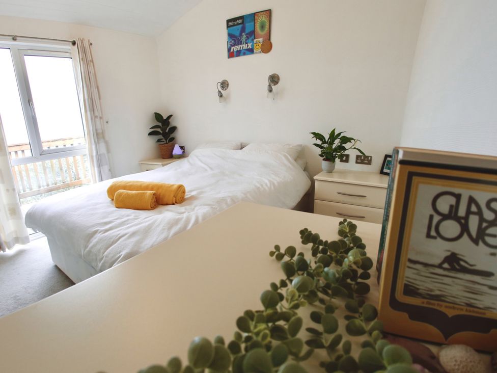 A bedroom with a bed and plant at Lowena Lodge Whitsand Bay Holiday Park near Millbrook