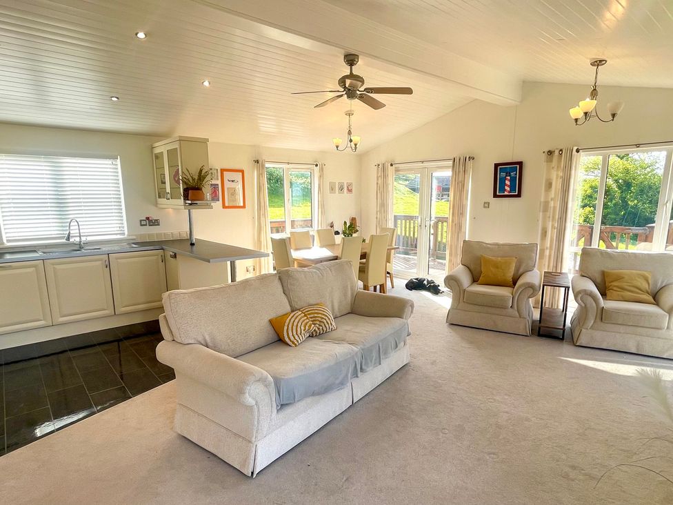 A living room with a sofa and dining area at Lowena Lodge Whitsand Bay Holiday Park near Millbrook