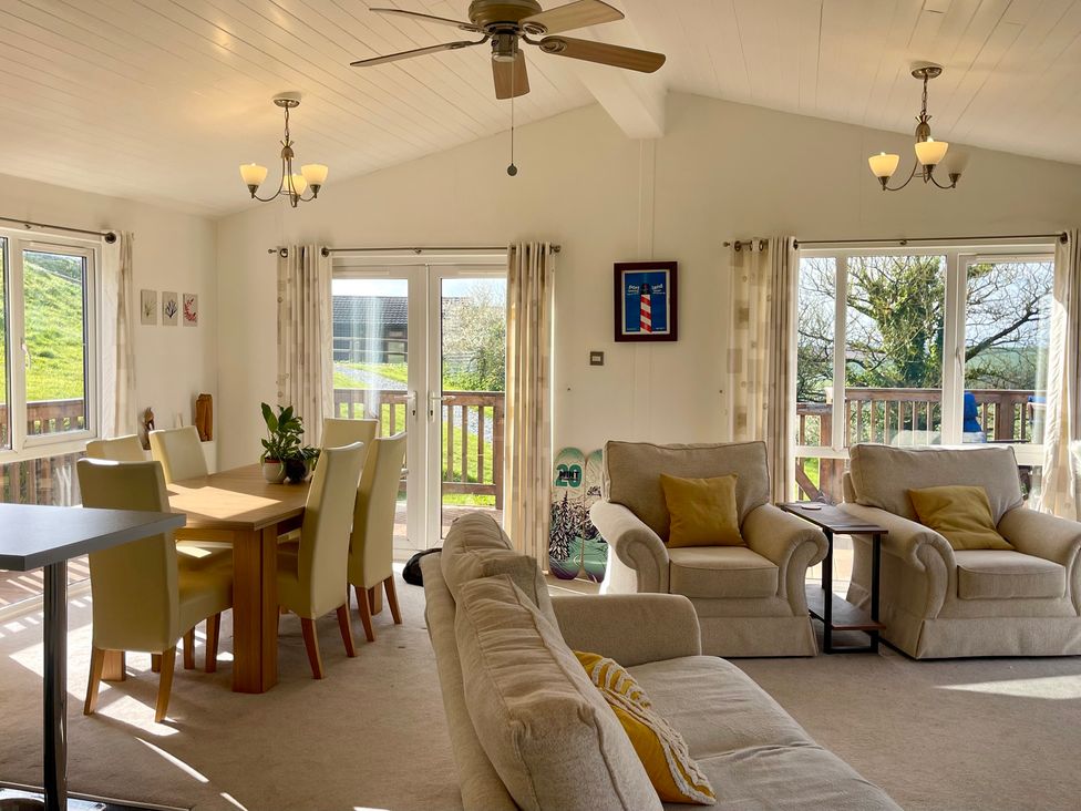 A living room with a dining table and chairs, sofa, and a coffee table at Lowena Lodge Whitsand Bay Holiday Park near Millbrook
