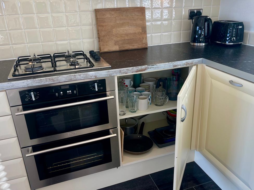 A kitchen with a gas stove, oven, and kitchenware at Lowena Lodge Whitsand Bay Holiday Park near Millbrook