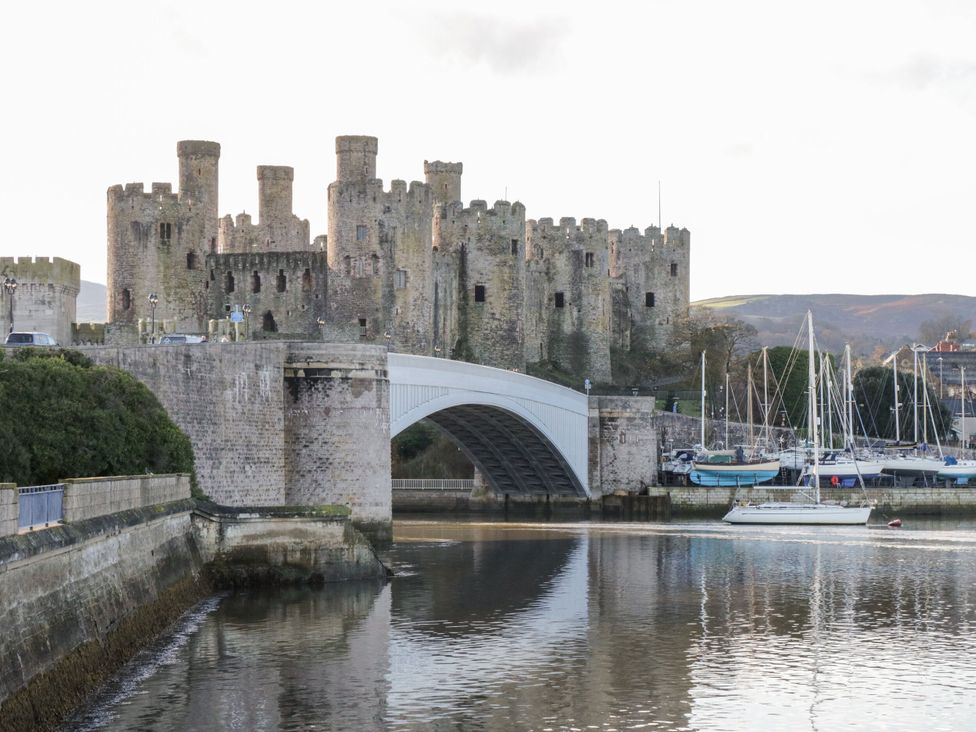 A castle with a bridge over water and boats at Conwy