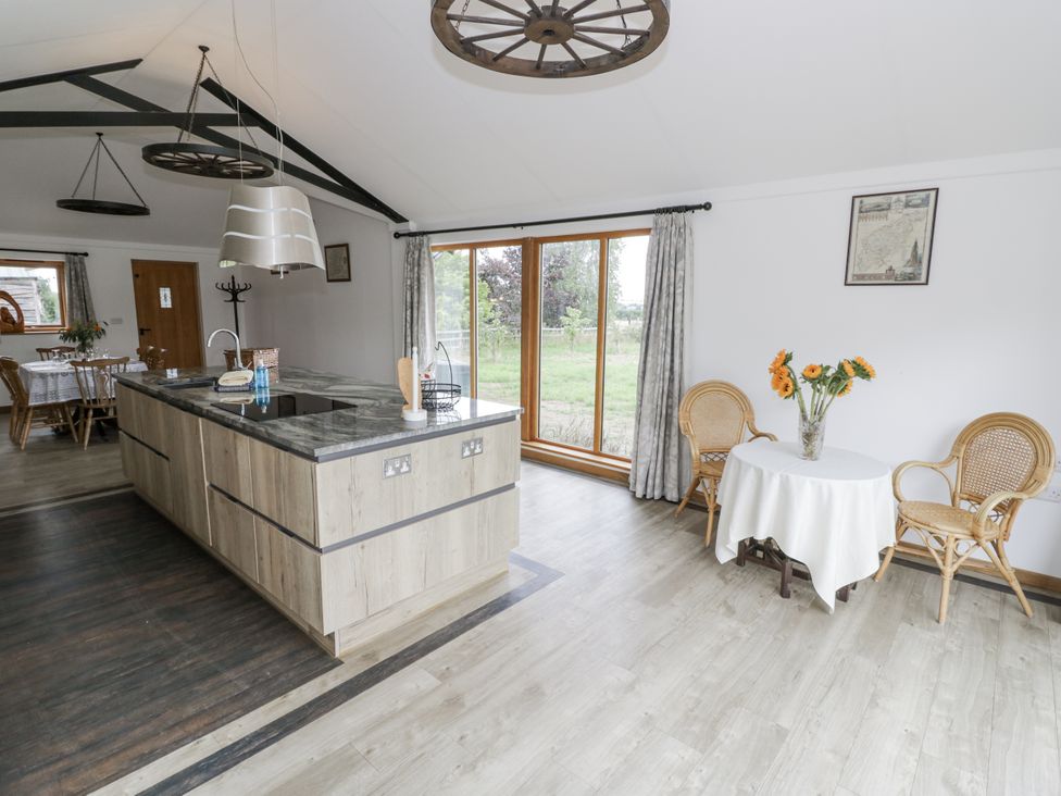 A kitchen with a dining area and flowers on a table at Owl Barn in Banbury