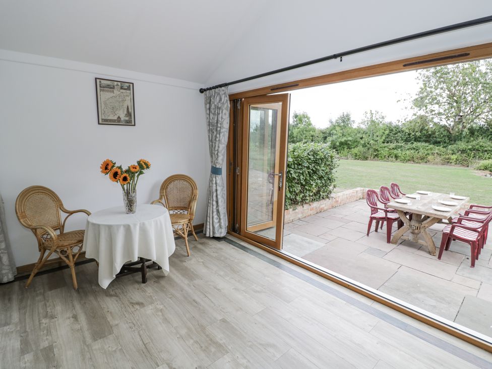 A dining room with a table and chairs leading to outdoor seating at Owl Barn in Banbury