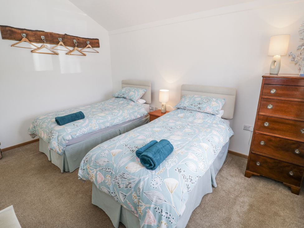 A bedroom with two beds and a dresser at Owl Barn in Banbury