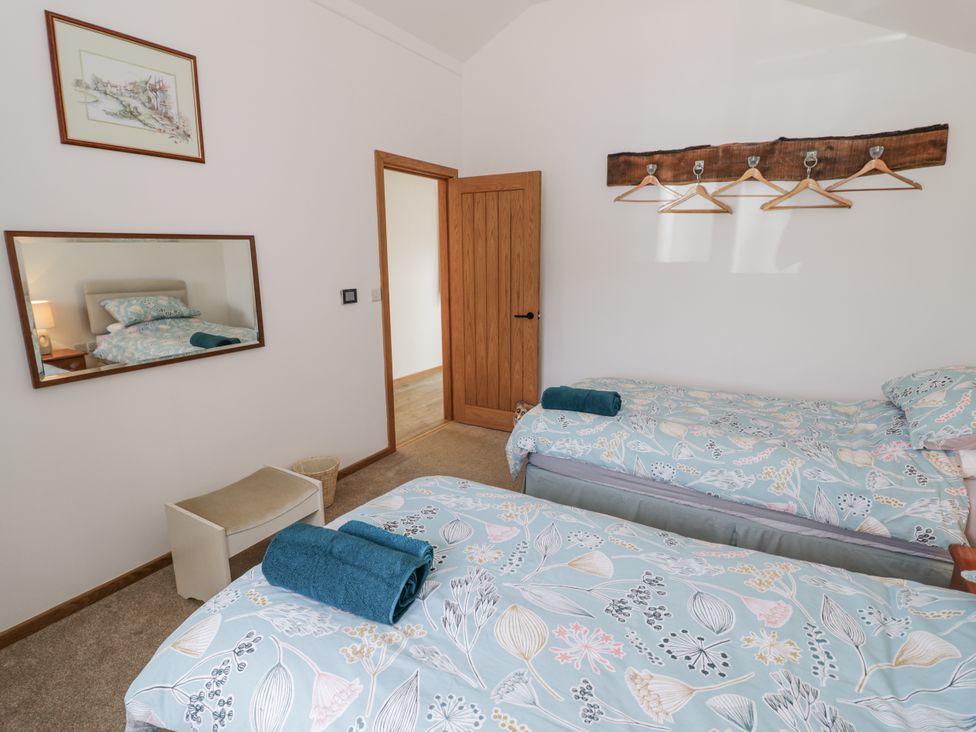 A bedroom with twin beds and a mirror at Owl Barn in Banbury