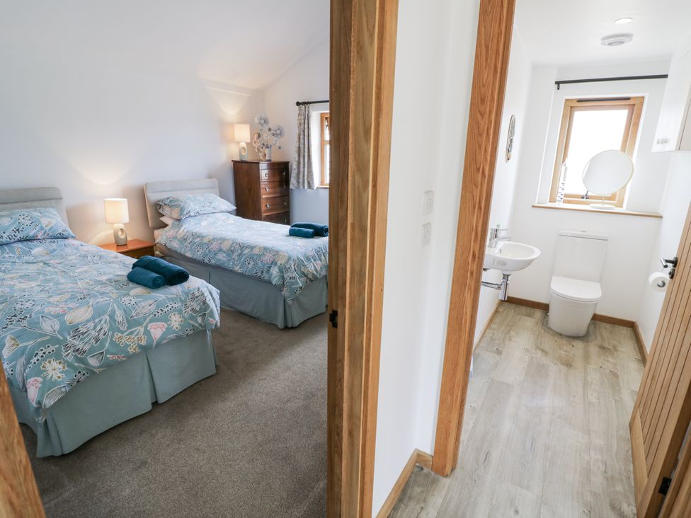 A bedroom with two beds and an adjoining bathroom at Owl Barn in Banbury