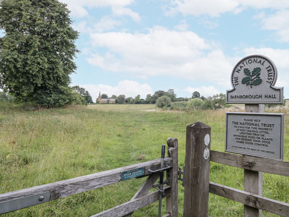 A grassy area with a gate and a sign at Farnborough Hall in Banbury