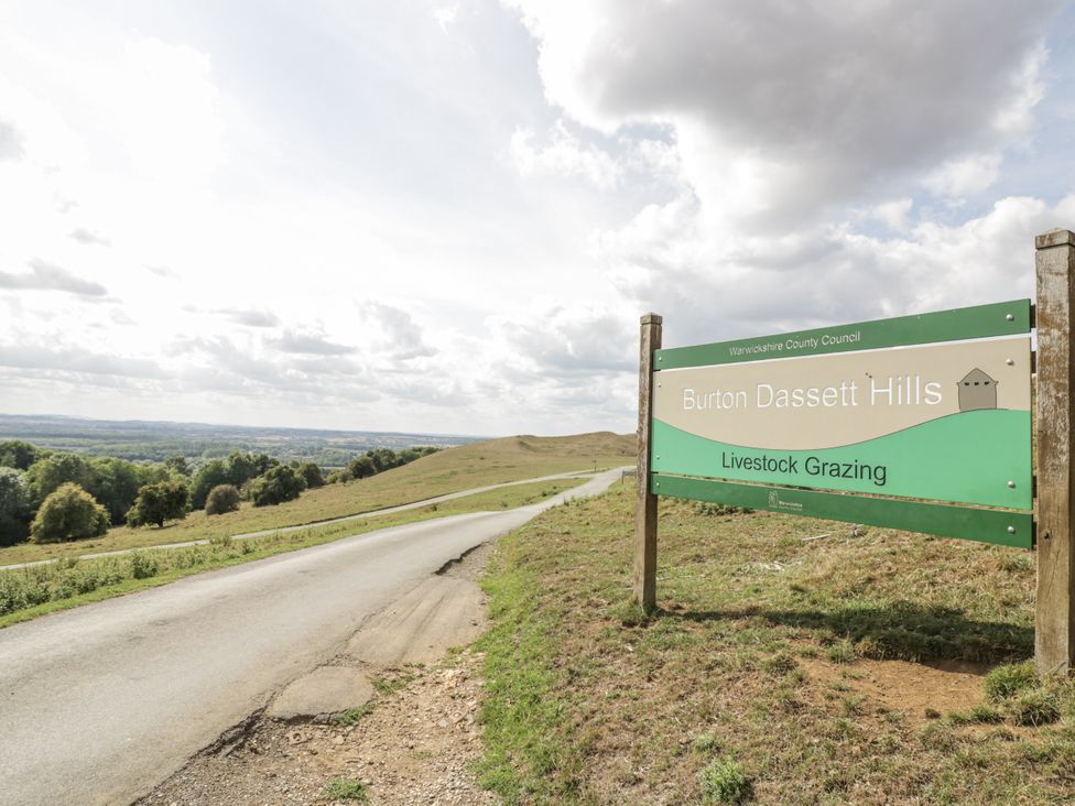 A sign for Burton Dassett Hills with grazing livestock at Burton Dassett Hills in Banbury