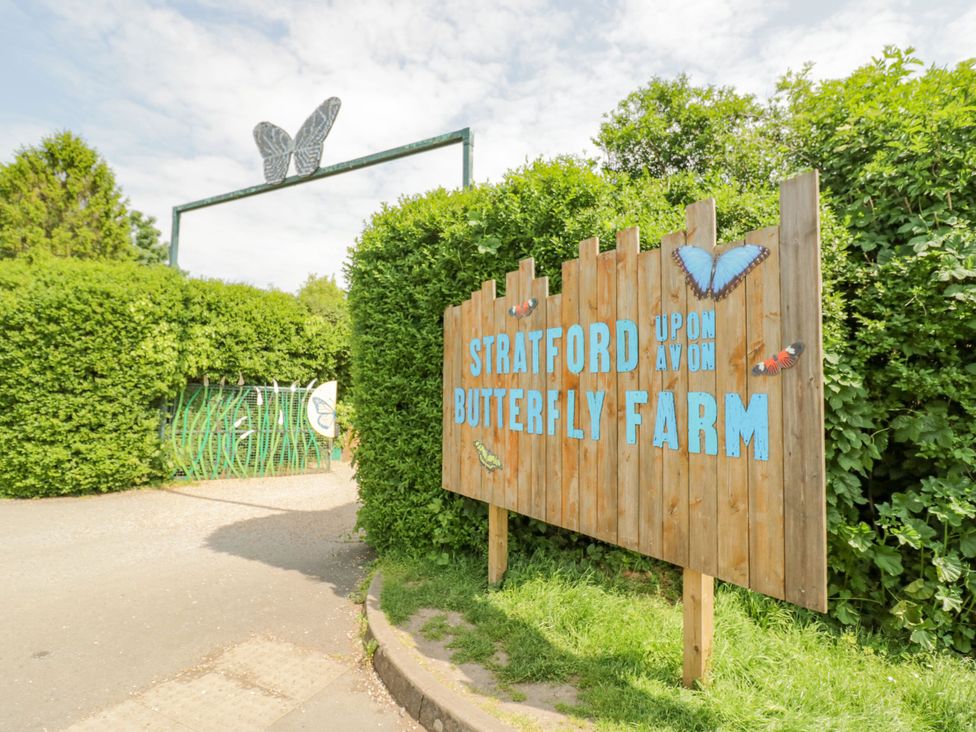 A sign at Stratford upon Avon Butterfly Farm with a hedge and pathway
