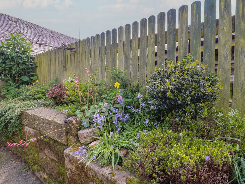 A garden with flowers and a wooden fence at Carr House Farm in Waberthwaite