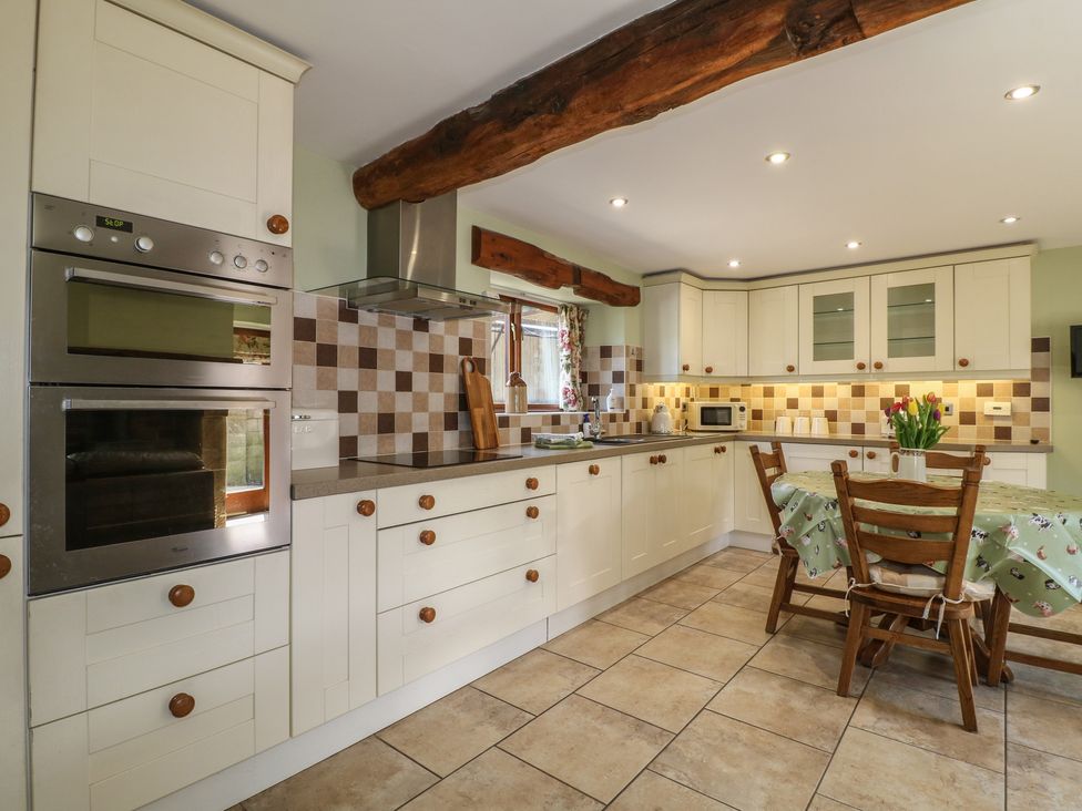 A kitchen with appliances and wooden dining table at Carr House Farm Waberthwaite