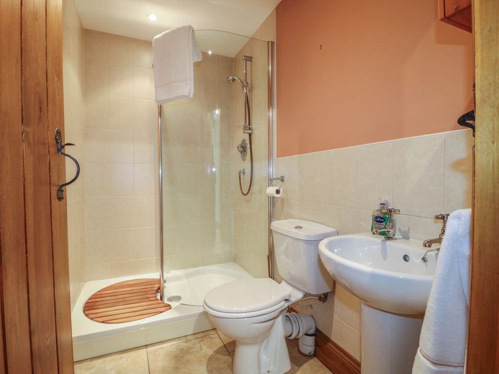 A bathroom with a shower, toilet, and wash basin at Carr House Farm in Waberthwaite