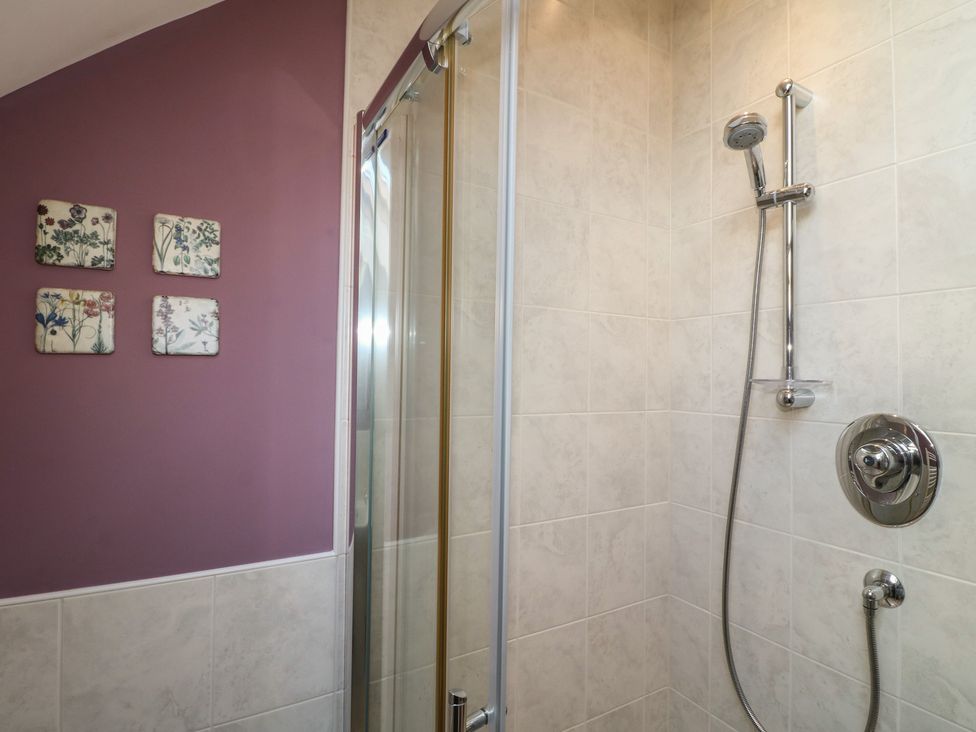 A bathroom with a shower and decorative tiles at Carr House Farm Waberthwaite
