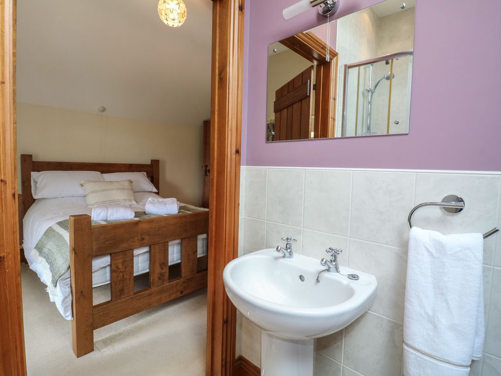 A bedroom with a wooden bed and a sink at Carr House Farm in Waberthwaite