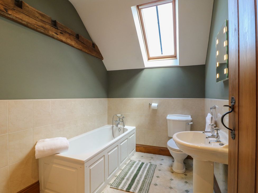 A bathroom with a bathtub, toilet, and sink at Carr House Farm Waberthwaite