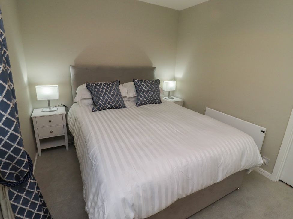 A bedroom with a bed and lamps on nightstands at 3 Longstone Park Beadnell