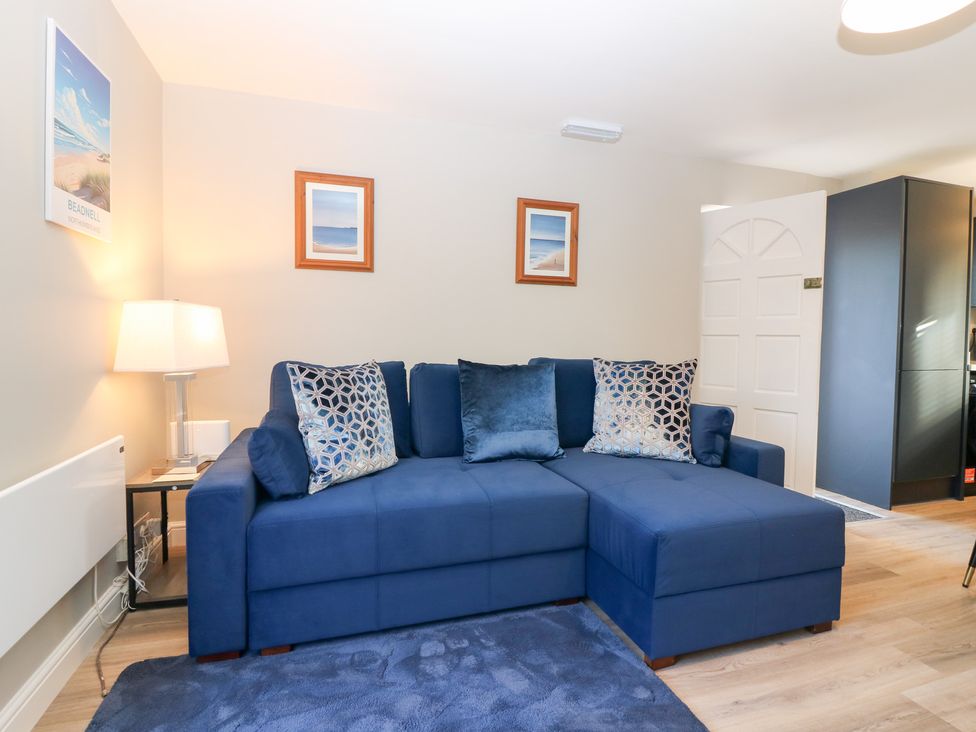 A living room with a blue sofa and lamp at Seaspray in Beadnell