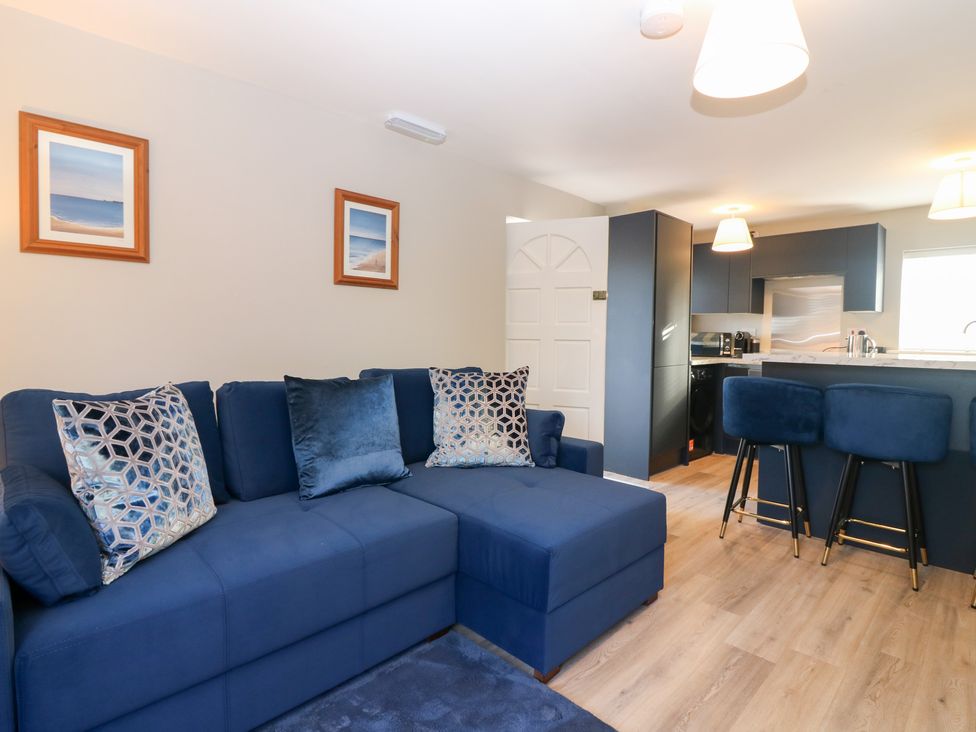 A living room with a sofa and kitchen island at Seaspray in Beadnell