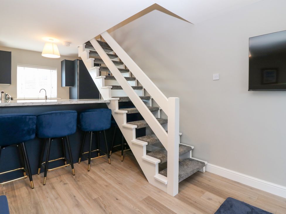A living room with stairs and bar stools at Seaspray in Beadnell