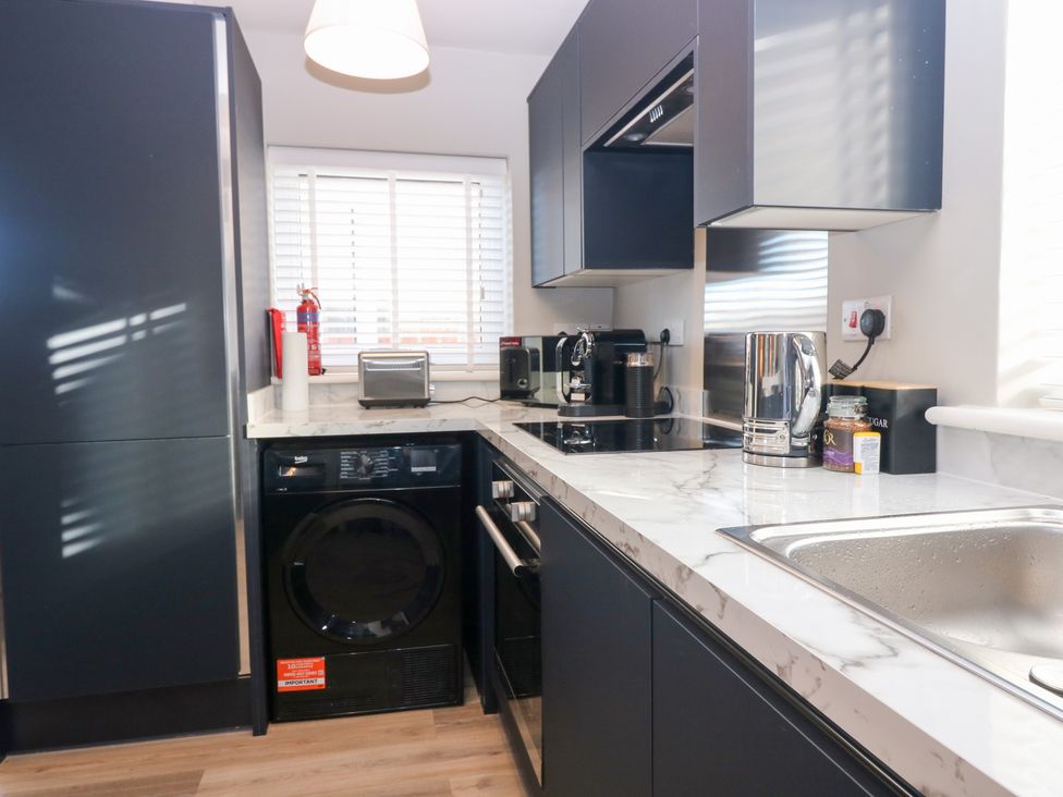 A kitchen with appliances including a washing machine and kettle at Seaspray in Beadnell