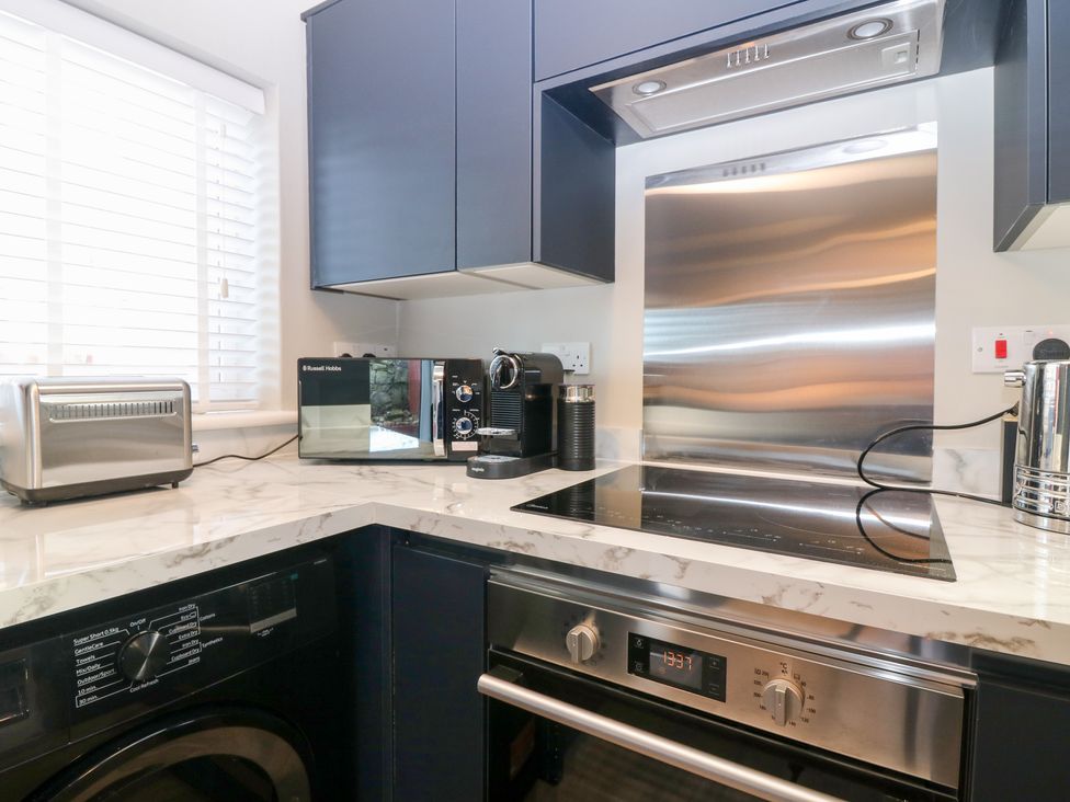 A kitchen with appliances including a washing machine and coffee machine at Seaspray in Beadnell