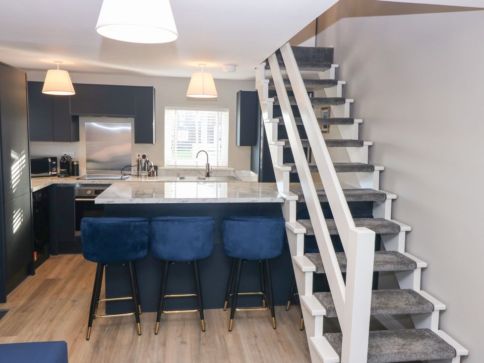 A kitchen with a marble island and bar stools at Seaspray in Beadnell