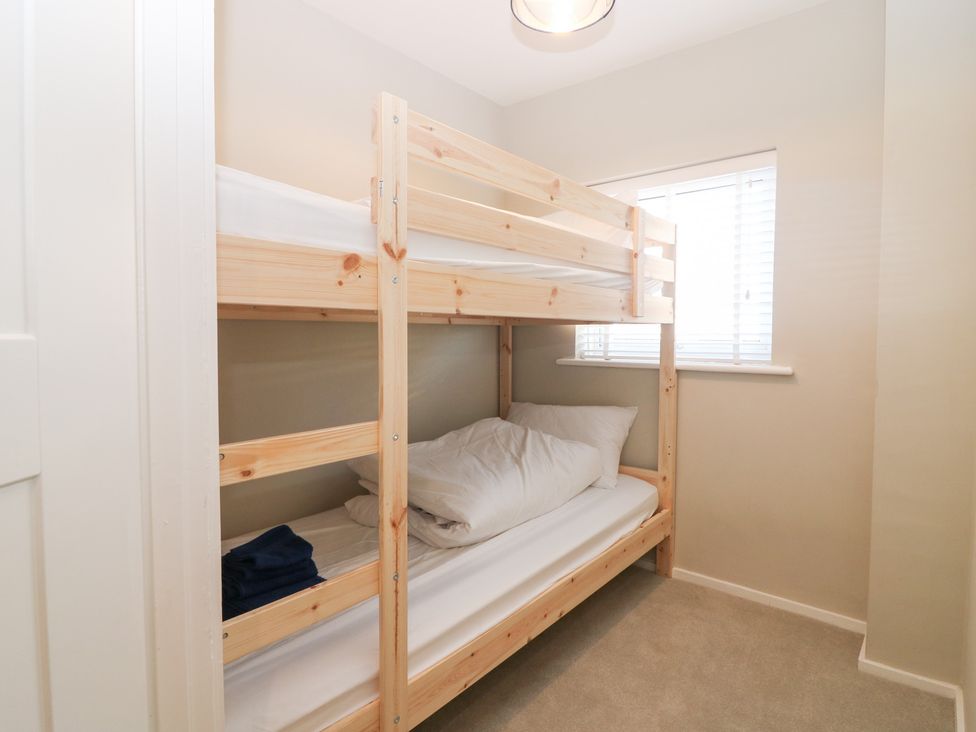 A bedroom with a bunk bed and window at Seaspray in Beadnell