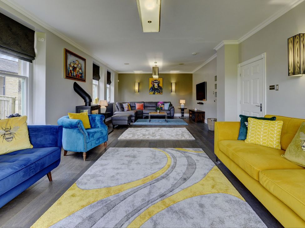 A living room with blue and yellow sofas and a coffee table at The Farm House near Aldbrough St. John