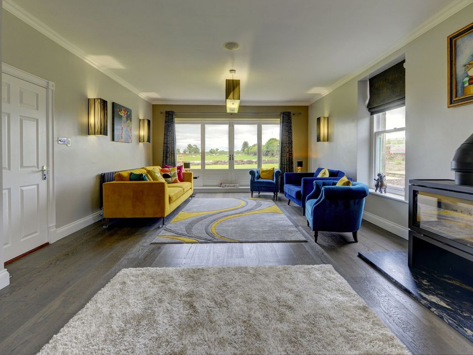 A living room with a yellow sofa and blue armchairs at The Farm House in Aldbrough St. John near Barton
