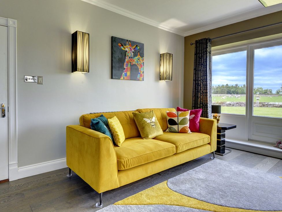 A living room with a yellow sofa and paintings at The Farm House in Aldbrough St. John near Barton