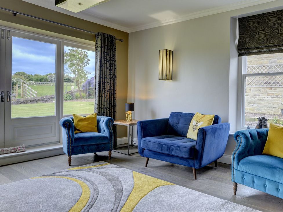 A living room with a blue sofa and armchairs at The Farm House in Aldbrough St. John near Barton