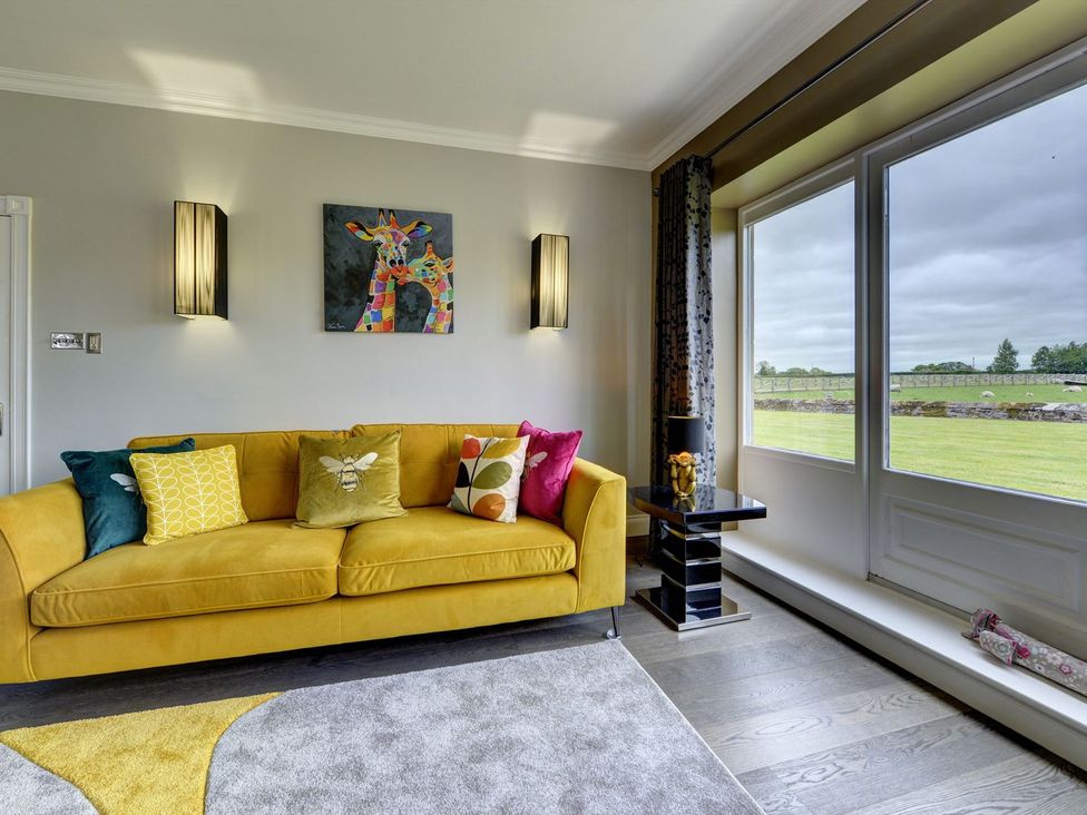 A living room with a yellow sofa and decorative cushions at The Farm House in Aldbrough St. John near Barton