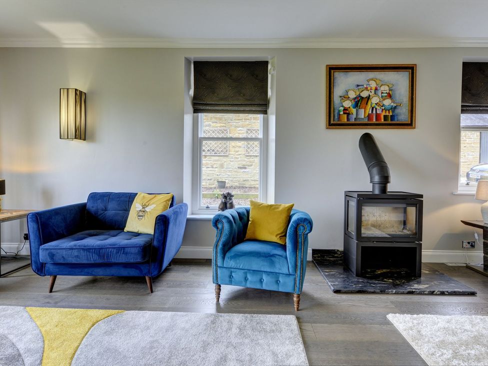 A living room with a sofa, armchair, and fireplace at The Farm House in Aldbrough St. John near Barton