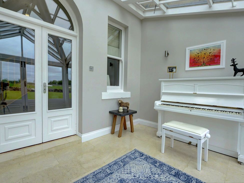 A room with a piano, table, and artwork at The Farm House in Aldbrough St. John near Barton