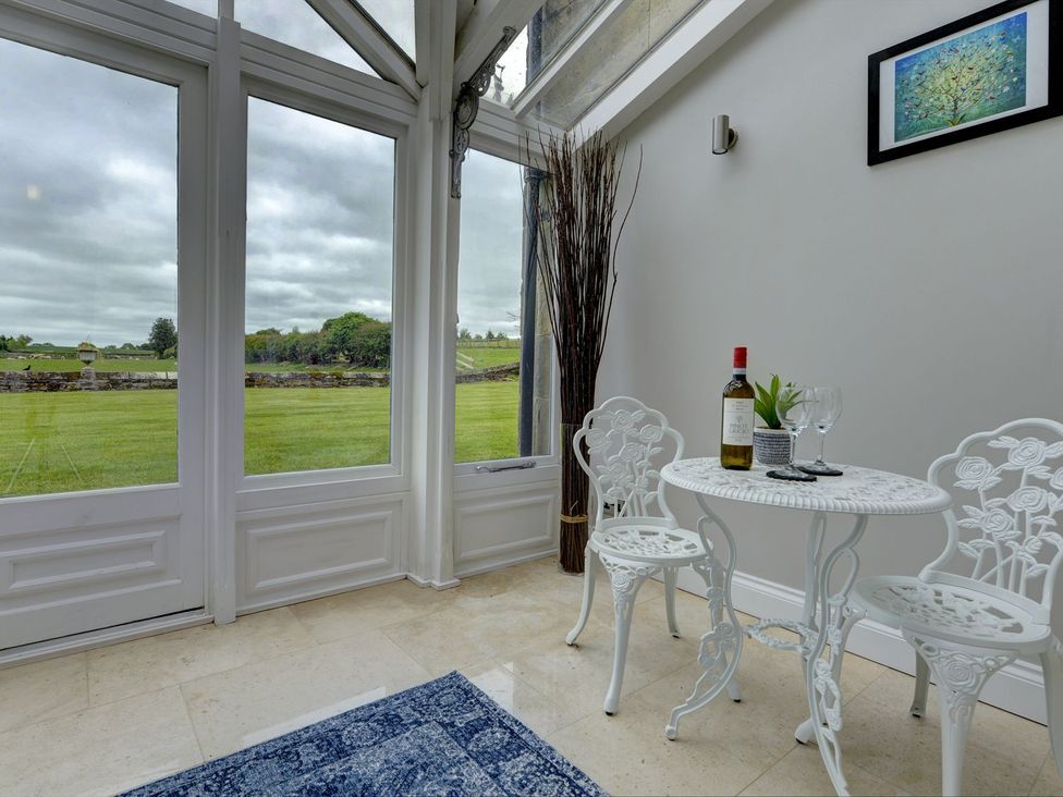 A conservatory with a table and chairs at The Farm House in Aldbrough St. John near Barton