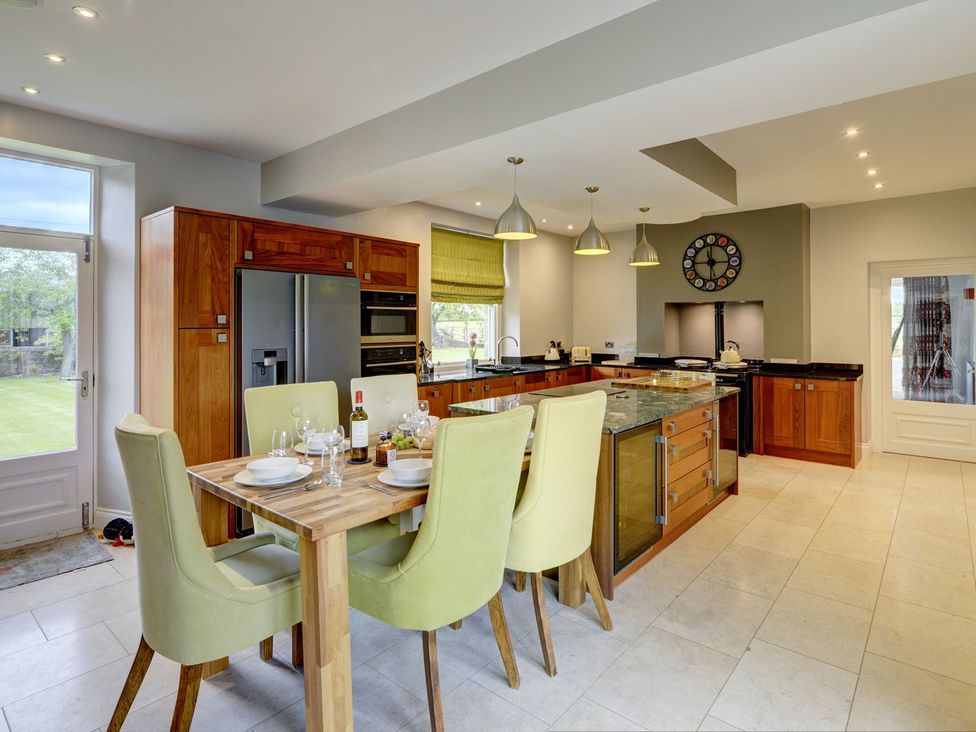 A kitchen with a dining table and stools at The Farm House in Aldbrough St. John near Barton