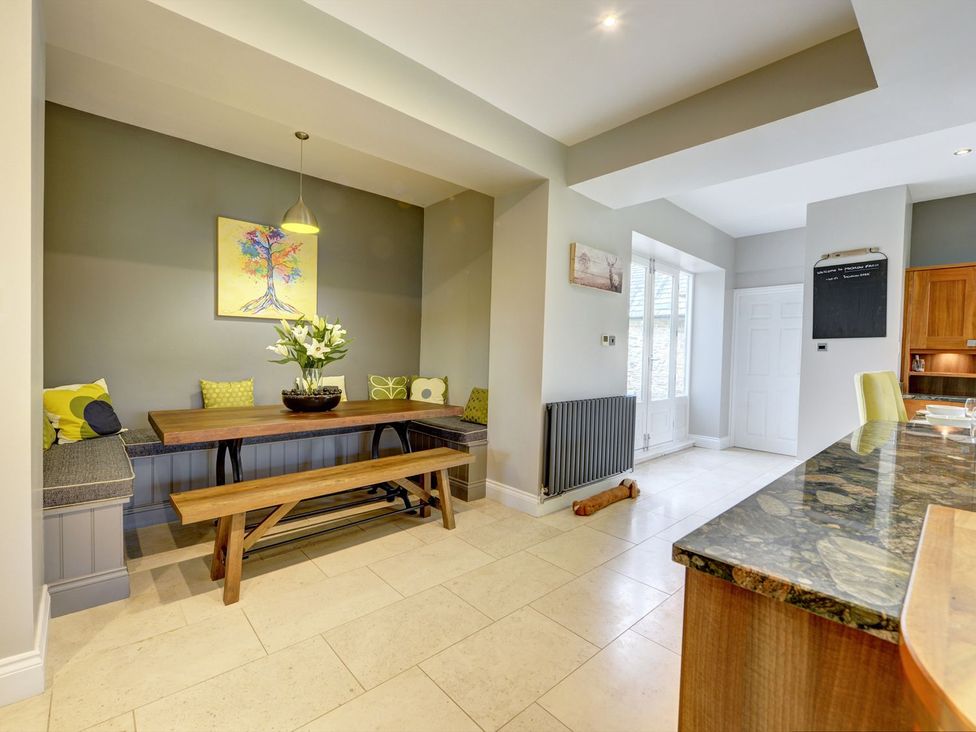 A dining room with a table and bench seating at The Farm House in Aldbrough St. John near Barton
