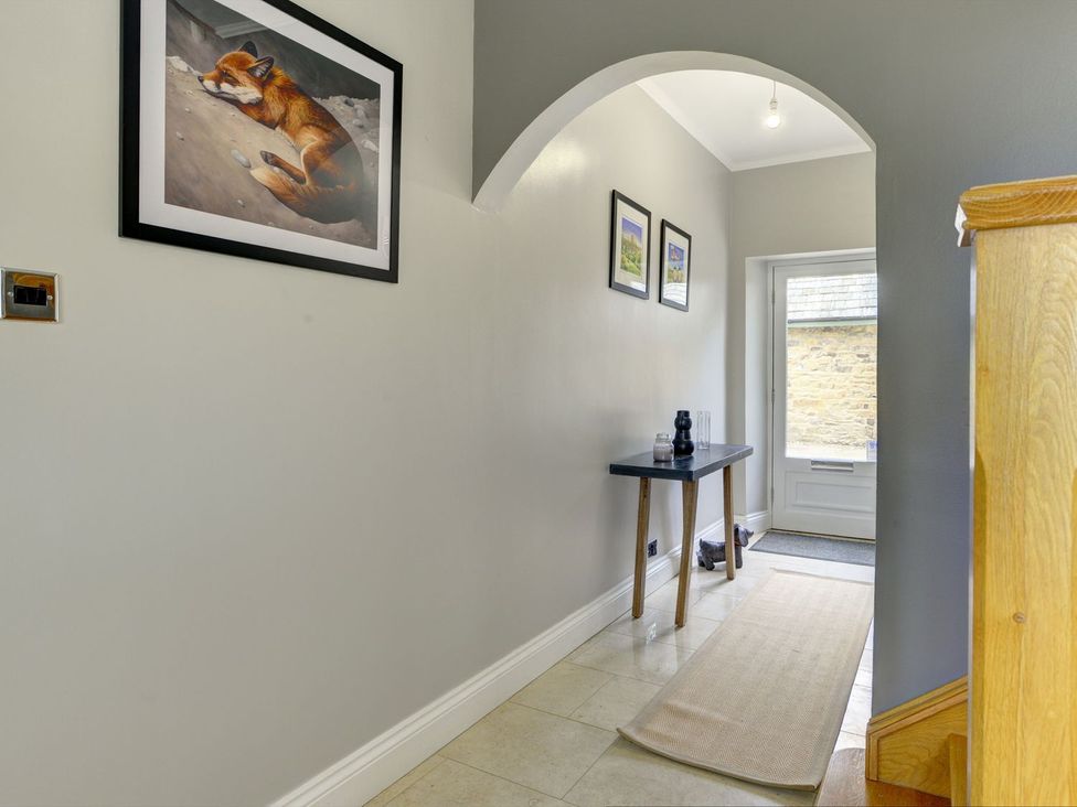 A hallway with a table and paintings on the wall at The Farm House in Aldbrough St. John near Barton