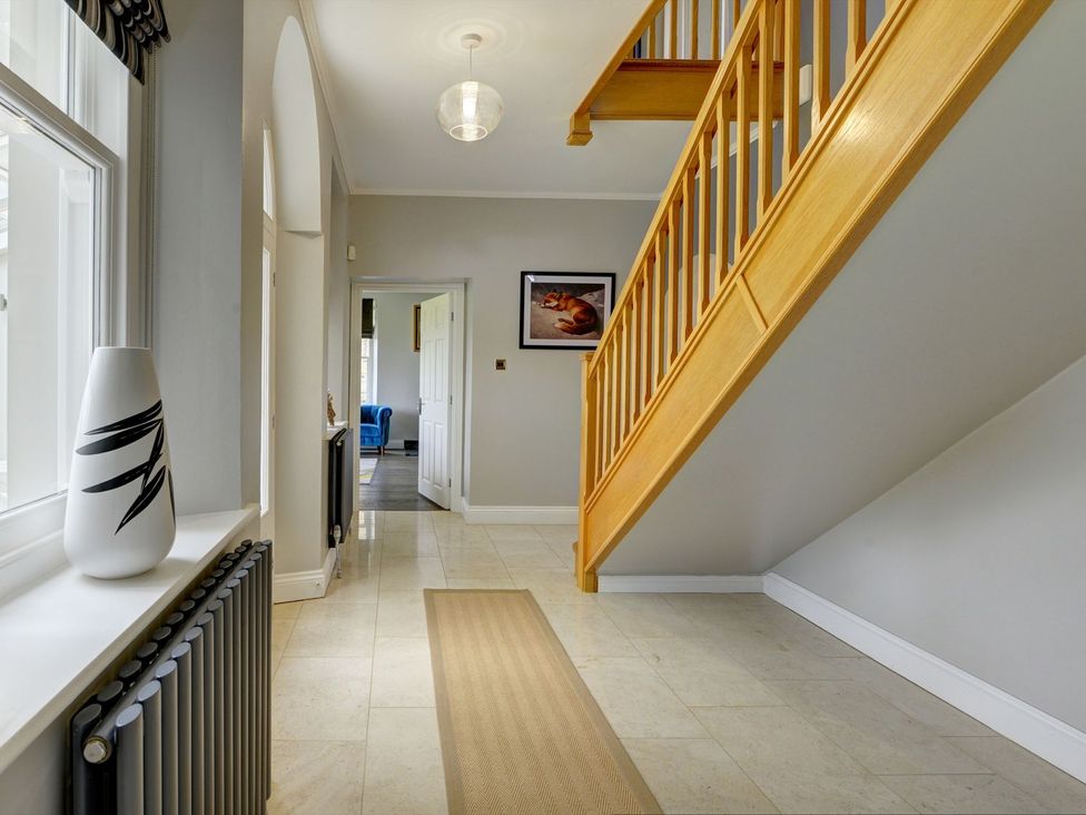 A hallway with a staircase and a vase at The Farm House in Aldbrough St. John near Barton