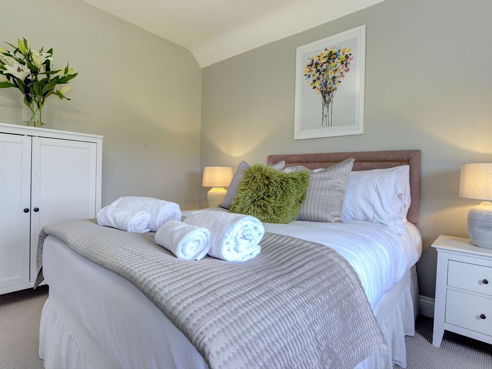 A bedroom with a bed and wardrobe at The Farm House in Aldbrough St. John near Barton