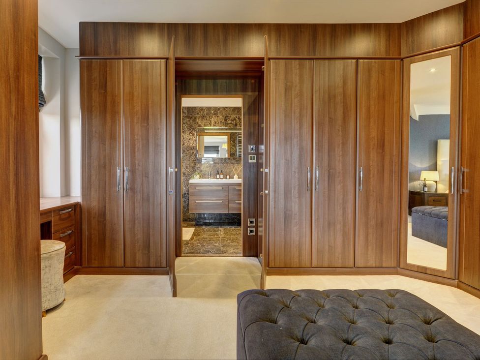 A bedroom with a wardrobe and an open bathroom door at The Farm House in Aldbrough St. John near Barton