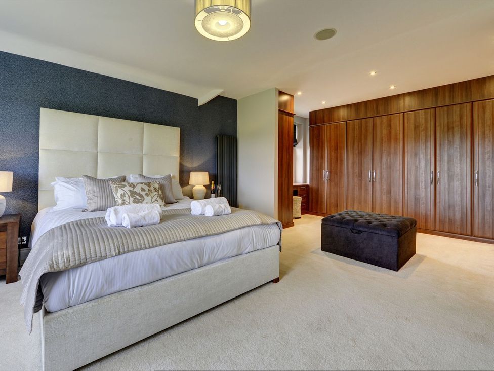 A bedroom with a bed and wardrobe at The Farm House in Aldbrough St. John near Barton