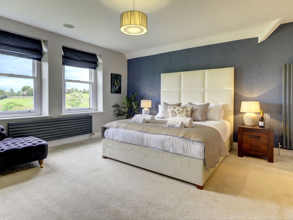 A bedroom with windows and a bed at The Farm House near Aldbrough St. John