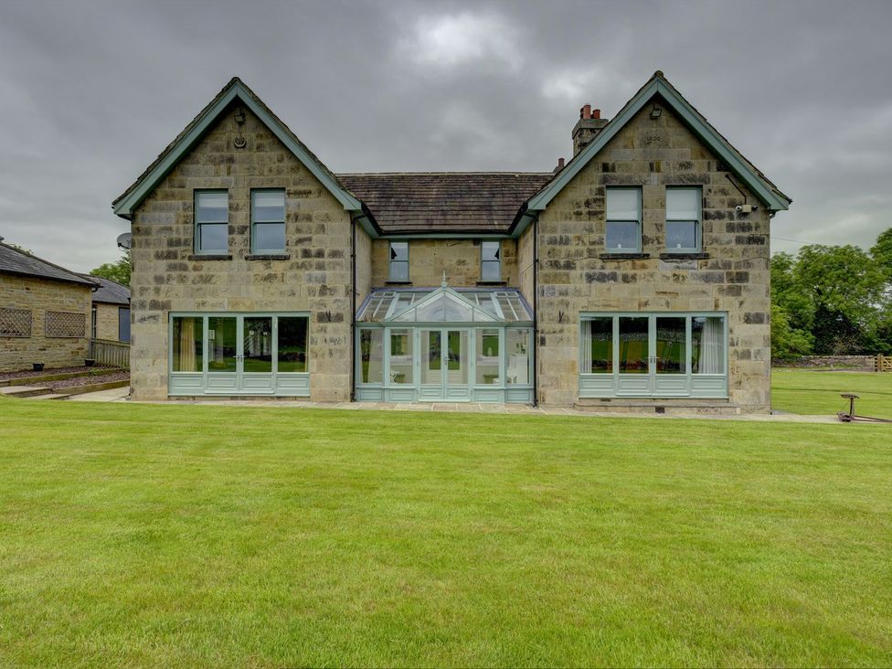 A house with a conservatory and lawn at The Farm House in Aldbrough St. John near Barton
