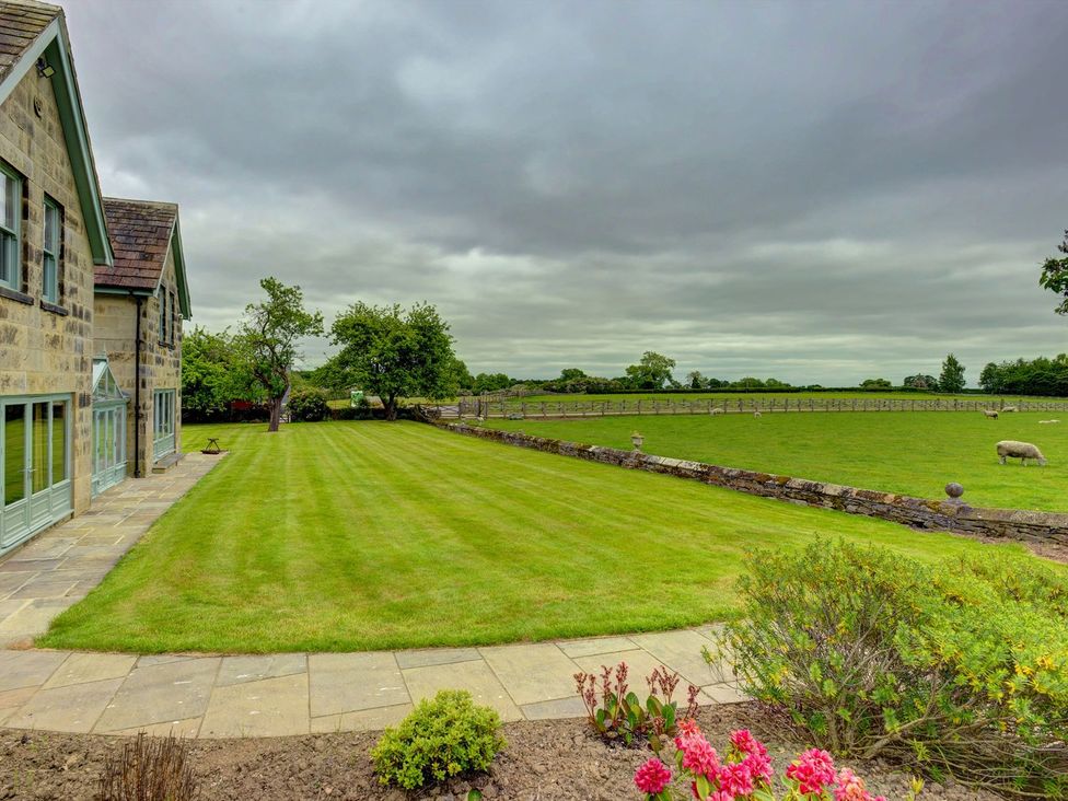 An outdoor area with a house, lawn, and sheep at The Farm House in Aldbrough St. John near Barton